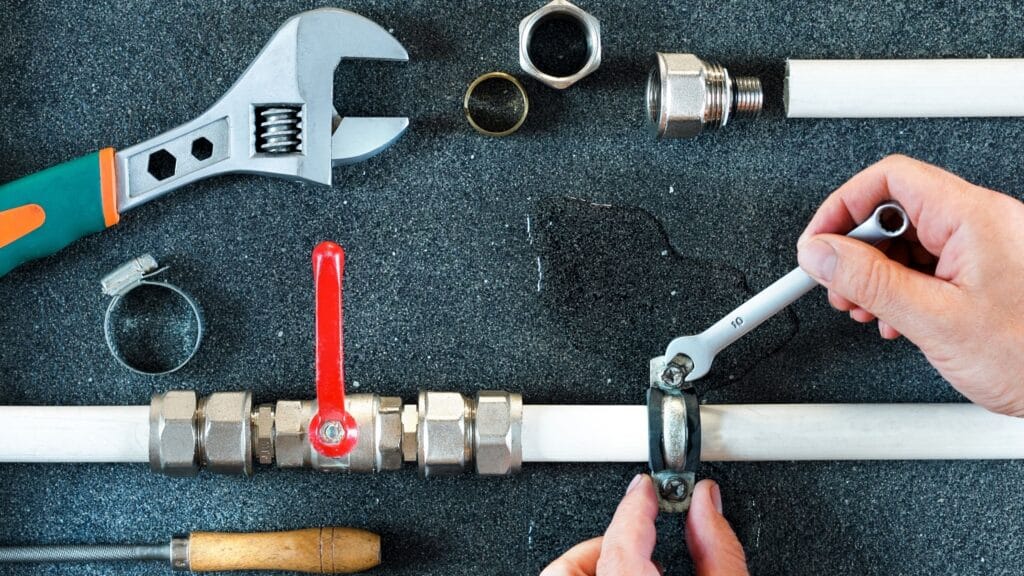 Plumber repairing a pipe valve with an adjustable wrench in Indio
