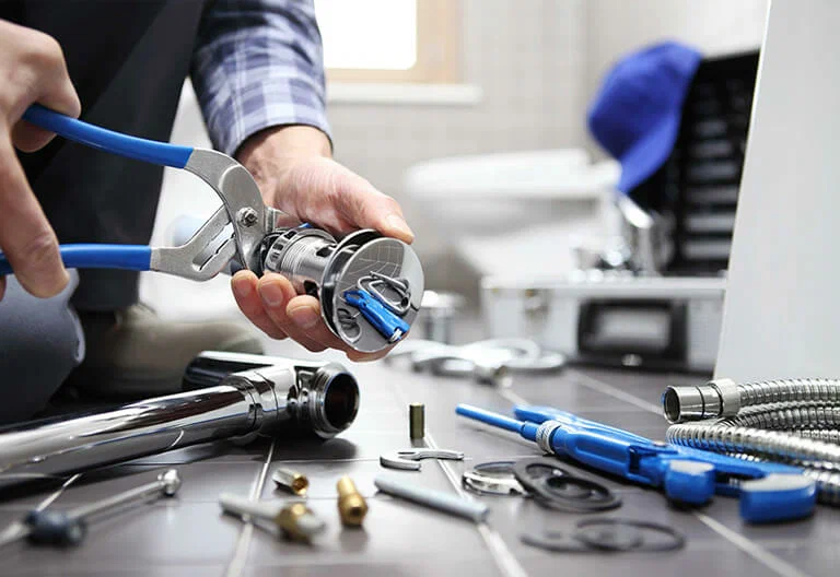 Technician repairing a plumbing fixture with professional tools in Indio